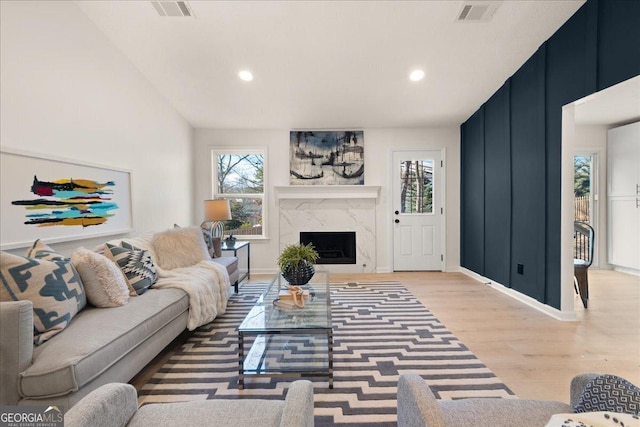 living room featuring wood-type flooring, vaulted ceiling, and a fireplace