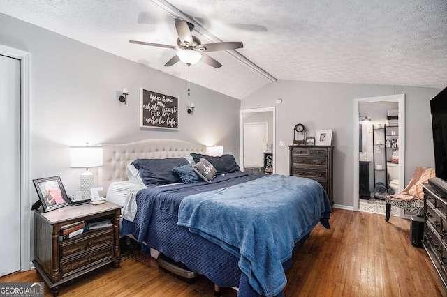 bedroom with hardwood / wood-style flooring, ensuite bath, ceiling fan, a textured ceiling, and vaulted ceiling