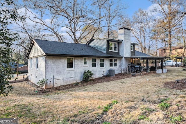 rear view of house with central AC unit and a lawn