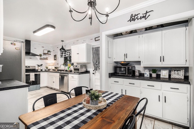 kitchen featuring wall chimney range hood, sink, stainless steel appliances, ornamental molding, and white cabinets