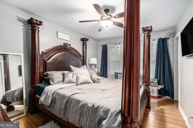 bedroom featuring hardwood / wood-style flooring, ceiling fan, and ornate columns