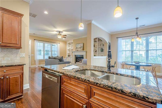 kitchen with decorative backsplash, built in features, dishwasher, and stone counters