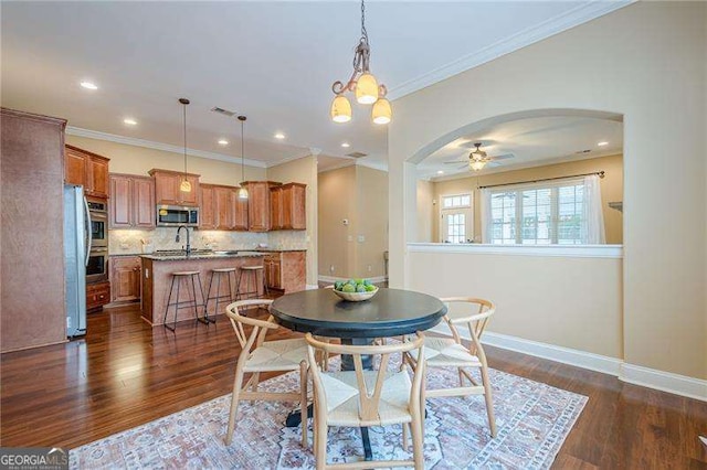 dining area featuring ornamental molding, dark hardwood / wood-style floors, and ceiling fan with notable chandelier