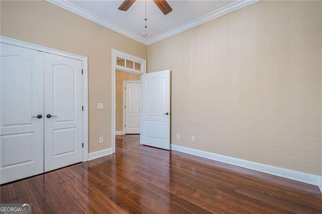 unfurnished bedroom with crown molding, dark hardwood / wood-style flooring, ceiling fan, and a closet