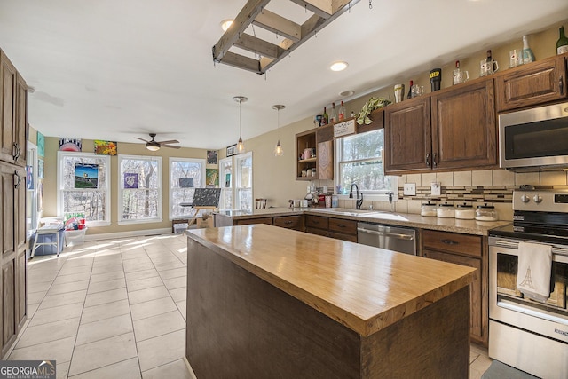 kitchen with sink, decorative backsplash, hanging light fixtures, light tile patterned floors, and stainless steel appliances