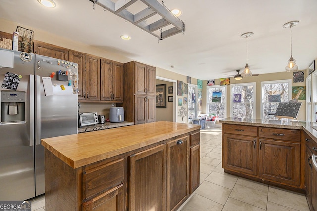 kitchen with stainless steel refrigerator with ice dispenser, wood counters, light tile patterned flooring, a center island, and ceiling fan