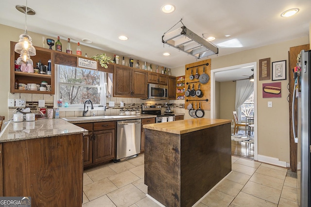 kitchen with sink, decorative light fixtures, appliances with stainless steel finishes, a kitchen island, and backsplash