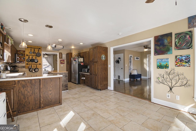 kitchen featuring sink, stainless steel fridge, hanging light fixtures, and ceiling fan