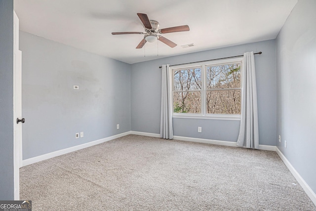 carpeted spare room with baseboards, ceiling fan, and visible vents