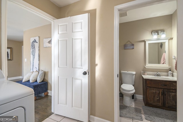 bathroom with tile patterned flooring, vanity, washer / dryer, and toilet