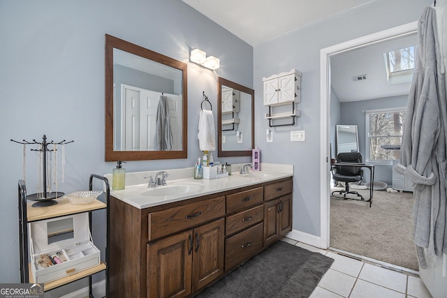 bathroom featuring vanity, lofted ceiling with skylight, and tile patterned flooring