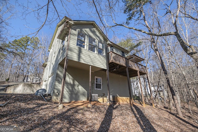 back of house with central air condition unit and a deck