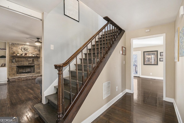 stairs with ceiling fan, hardwood / wood-style floors, and a fireplace