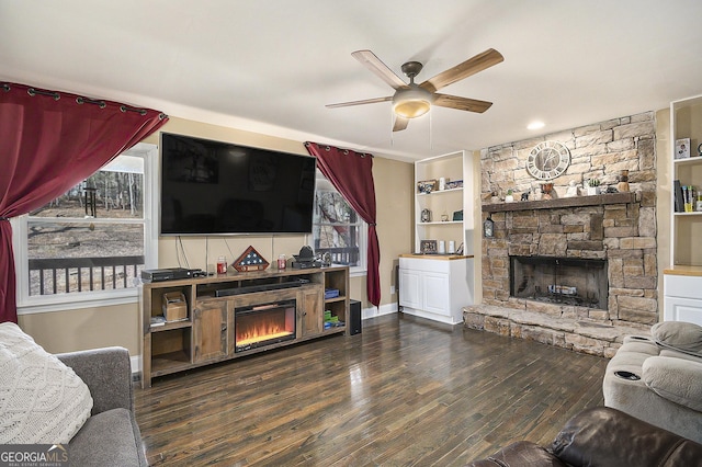 living room featuring ceiling fan, dark hardwood / wood-style floors, built in features, and a fireplace