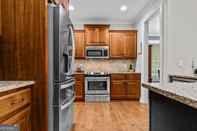 kitchen with appliances with stainless steel finishes, tasteful backsplash, light stone counters, ornamental molding, and light hardwood / wood-style floors