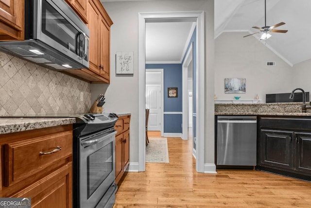 kitchen featuring appliances with stainless steel finishes, tasteful backsplash, sink, crown molding, and light hardwood / wood-style flooring