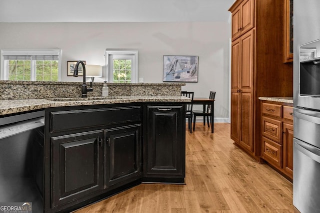 kitchen with dishwashing machine, sink, light stone counters, stainless steel fridge with ice dispenser, and light wood-type flooring