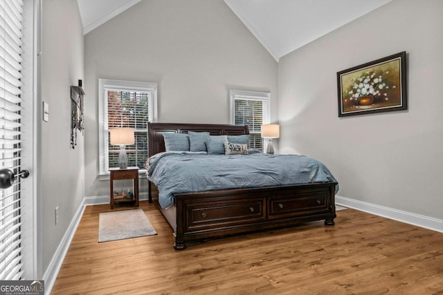 bedroom with crown molding, high vaulted ceiling, and hardwood / wood-style floors