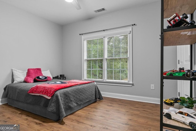 bedroom with ceiling fan, hardwood / wood-style floors, and multiple windows