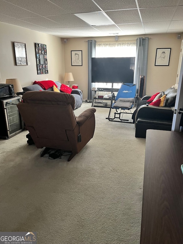 carpeted living room featuring a drop ceiling