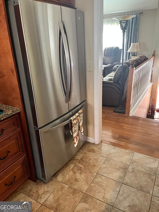 kitchen featuring stone countertops, light tile patterned floors, and stainless steel fridge