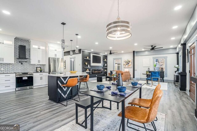 dining space featuring ceiling fan with notable chandelier and light hardwood / wood-style floors