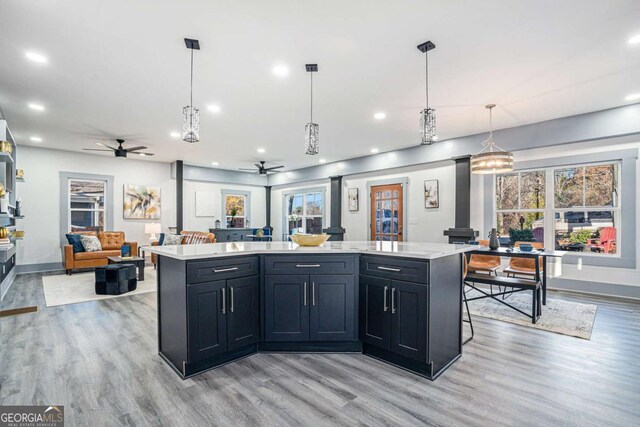 kitchen featuring a kitchen island, decorative light fixtures, a wood stove, light hardwood / wood-style floors, and a healthy amount of sunlight