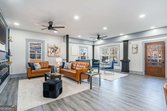 living room with a wood stove, ceiling fan, and light hardwood / wood-style flooring