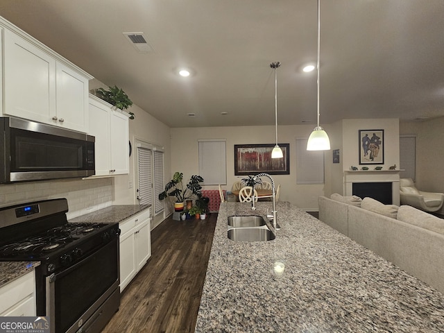 kitchen featuring tasteful backsplash, pendant lighting, appliances with stainless steel finishes, and white cabinets