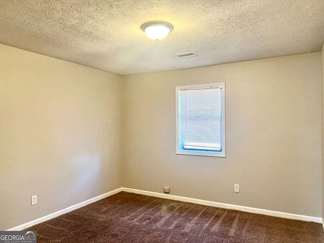 carpeted empty room featuring a textured ceiling