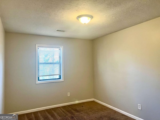 carpeted empty room featuring a textured ceiling