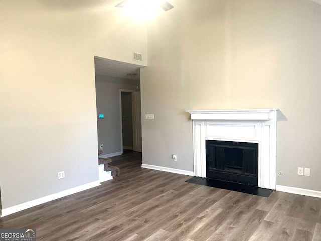 unfurnished living room with dark hardwood / wood-style flooring and a high ceiling