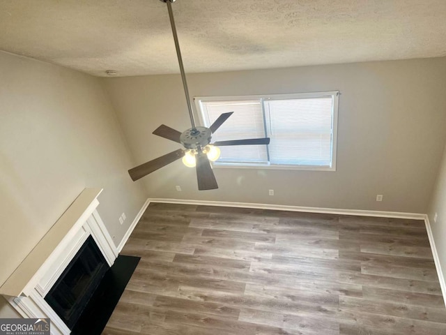 unfurnished living room featuring dark hardwood / wood-style flooring, ceiling fan, and a textured ceiling