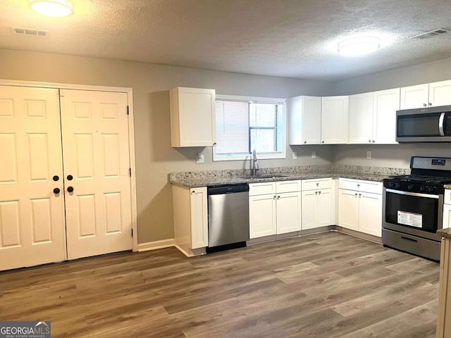 kitchen with white cabinetry, appliances with stainless steel finishes, dark hardwood / wood-style flooring, and sink