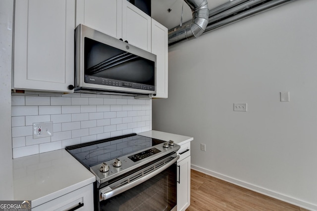 kitchen with white cabinetry, decorative backsplash, stainless steel appliances, and light hardwood / wood-style flooring