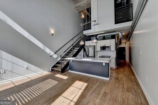 kitchen with tasteful backsplash, light hardwood / wood-style flooring, pendant lighting, stainless steel appliances, and white cabinets