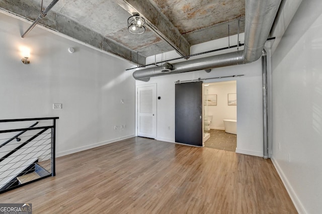 basement with a barn door and hardwood / wood-style floors