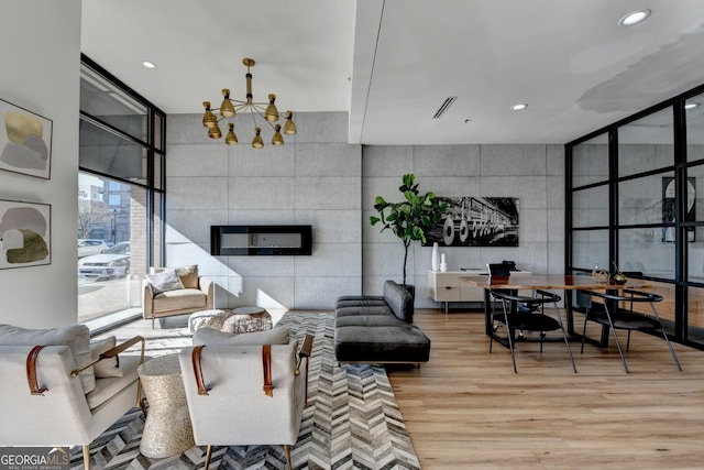 living room featuring a tile fireplace, expansive windows, a chandelier, and light wood-type flooring