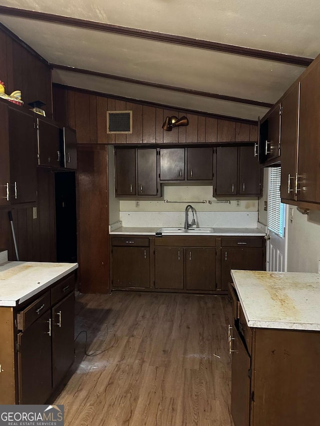 kitchen featuring dark wood-type flooring, sink, dark brown cabinets, and vaulted ceiling with beams