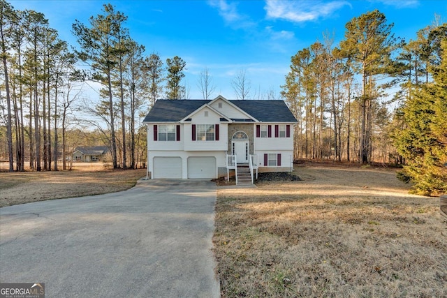 raised ranch featuring a garage and a front lawn