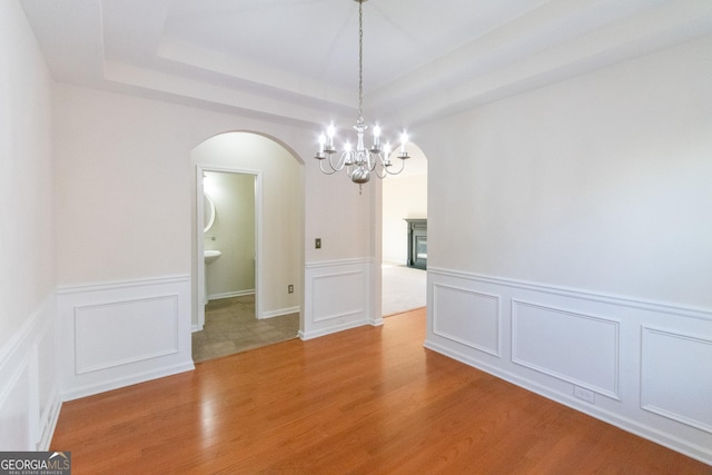 unfurnished room with hardwood / wood-style floors and a tray ceiling