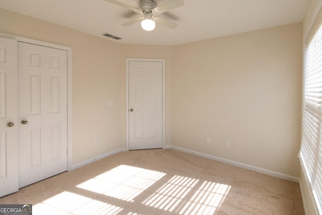 unfurnished bedroom featuring light carpet, a closet, and ceiling fan