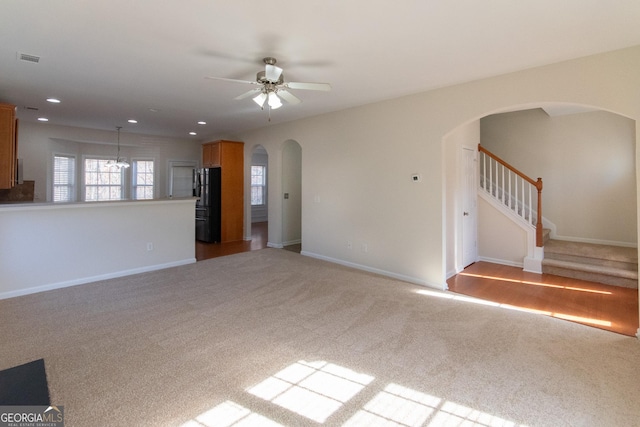 unfurnished living room with light colored carpet and ceiling fan