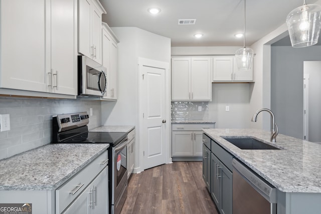 kitchen with dark wood-style floors, stainless steel appliances, visible vents, white cabinets, and a sink