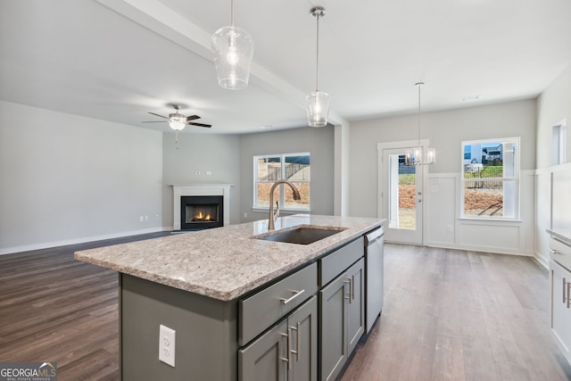 kitchen featuring a warm lit fireplace, dishwasher, dark wood-style flooring, gray cabinetry, and a sink