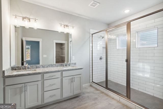 full bath with double vanity, a stall shower, visible vents, and a sink