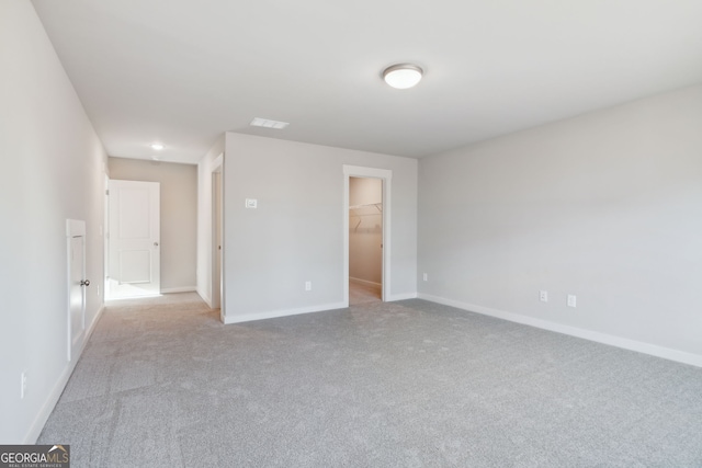 unfurnished bedroom featuring a spacious closet, a closet, carpet, and baseboards