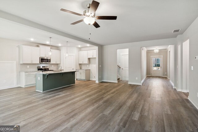 kitchen with appliances with stainless steel finishes, wood finished floors, and white cabinetry