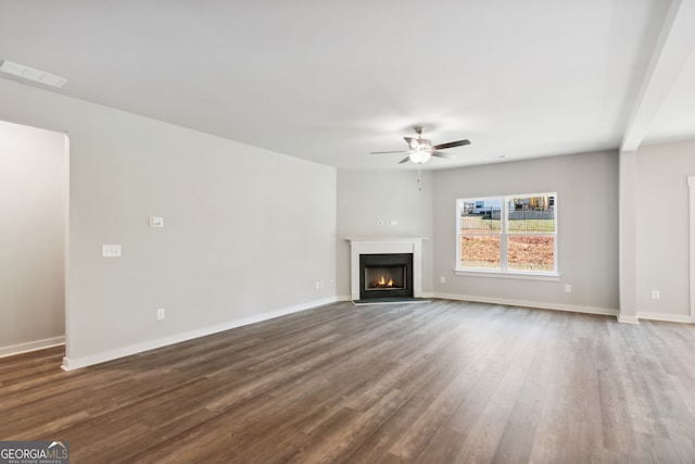 unfurnished living room featuring dark wood-style flooring, a fireplace with flush hearth, visible vents, a ceiling fan, and baseboards