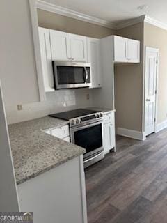 kitchen featuring appliances with stainless steel finishes, white cabinets, dark hardwood / wood-style flooring, ornamental molding, and light stone counters